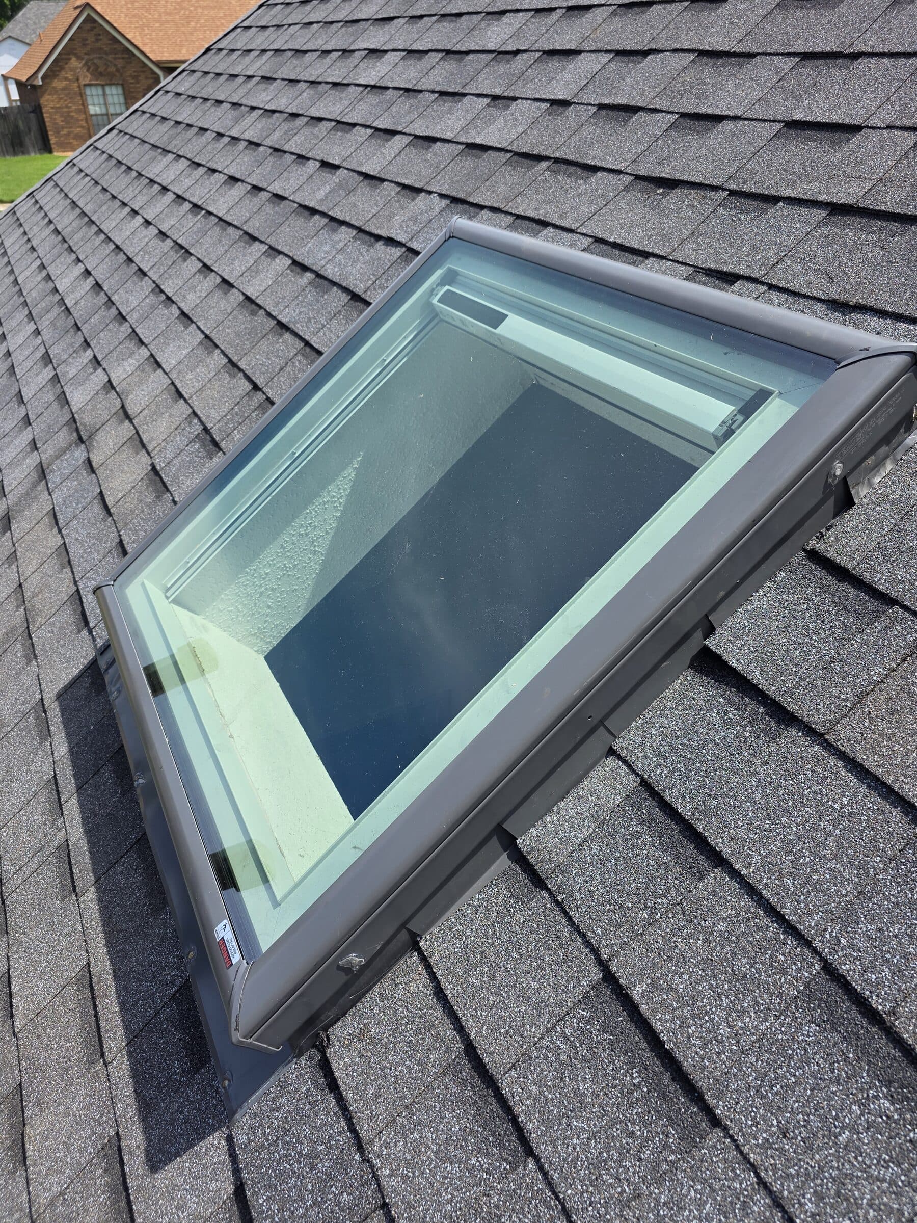 Skylight seen from above on dark architectural shingles
