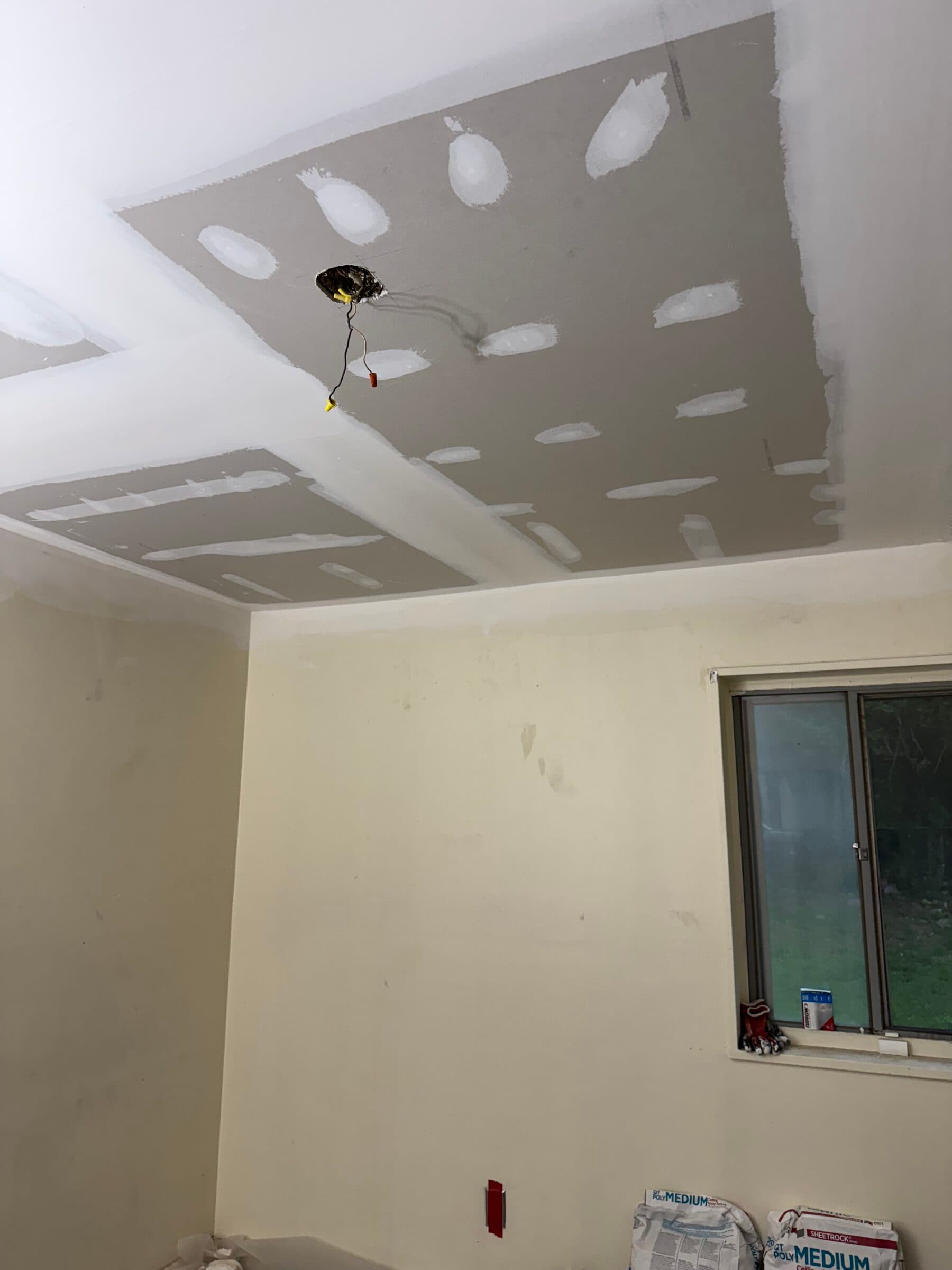 New ceiling drywall with taped and mudded joints around a light fixture opening