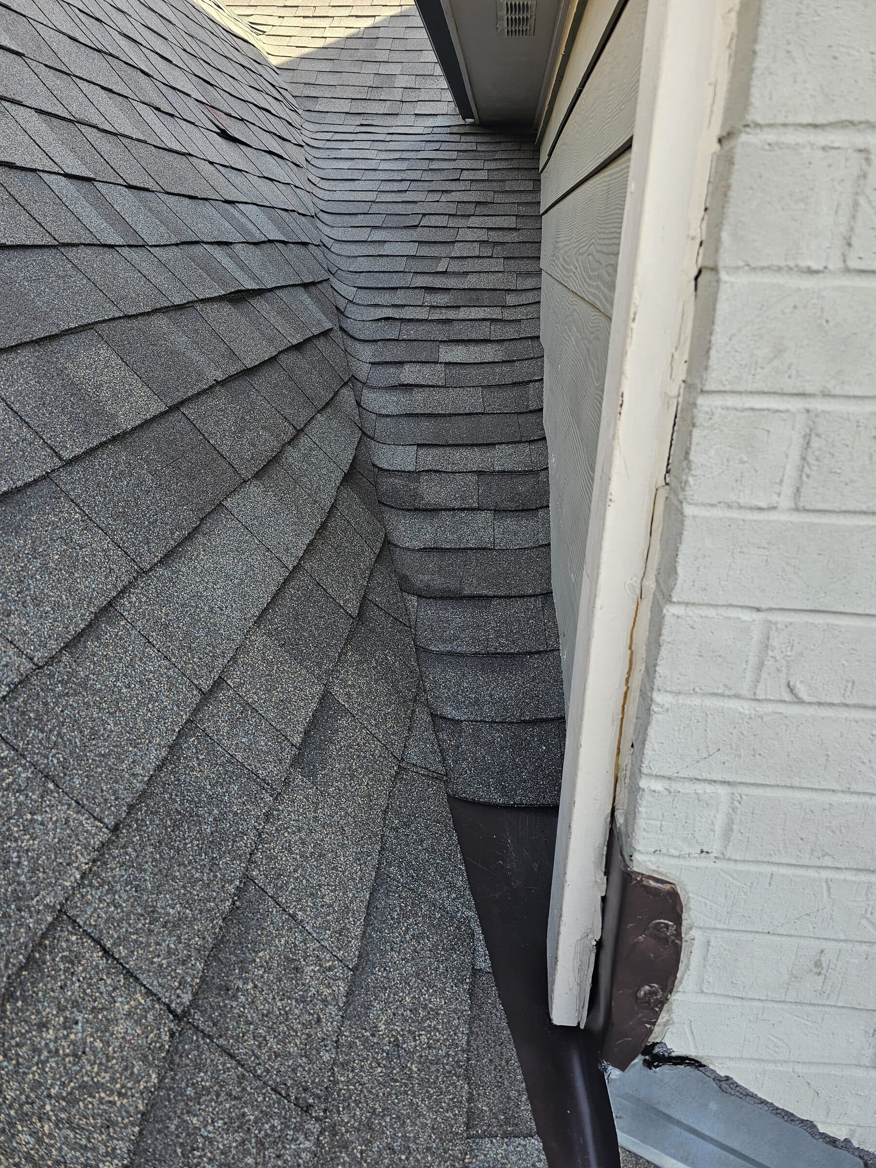 Close-up of a woven shingle valley beneath a boxed eave on a new architectural shingle roof