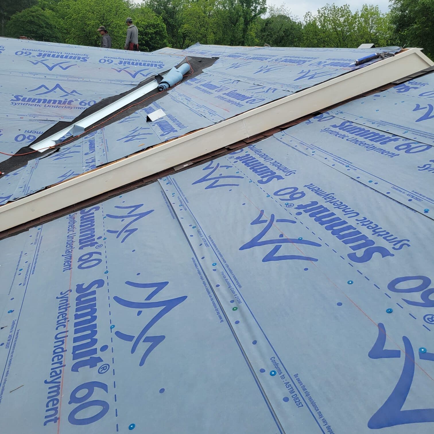 Blue synthetic underlayment installed across a roof deck mid-replacement
