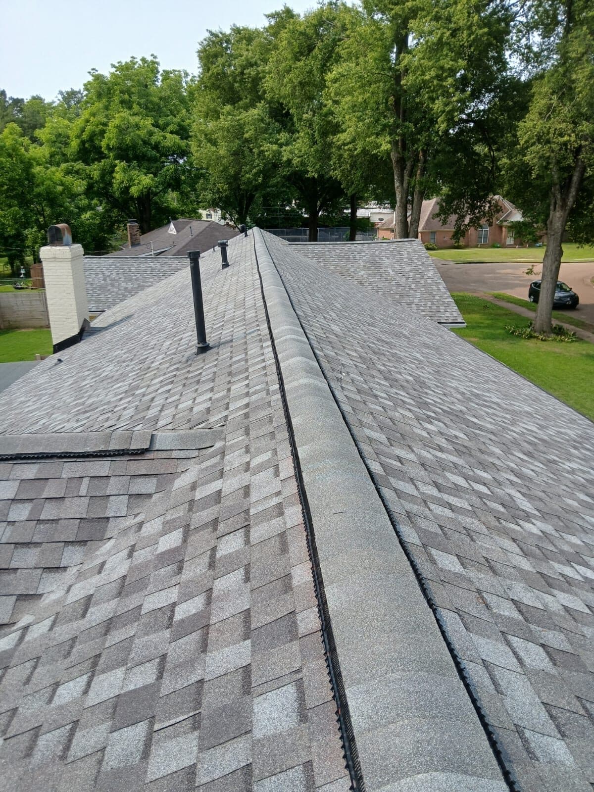 View down a long new shingle ridge toward a tree-lined street