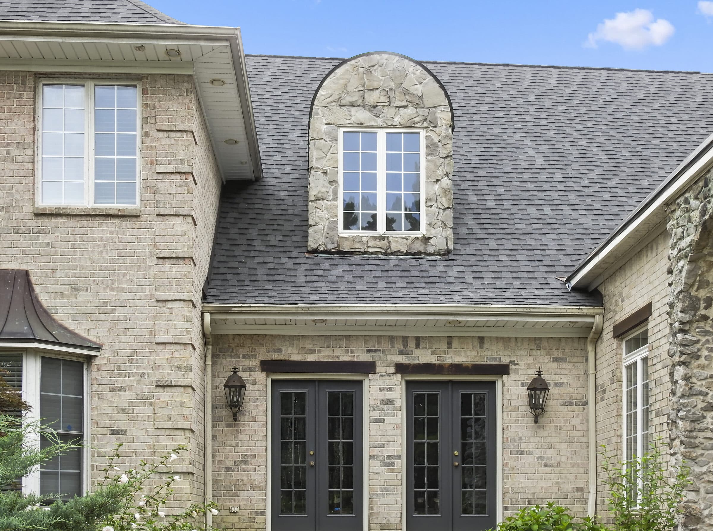 Stone French country style home with arched windows and double entry doors