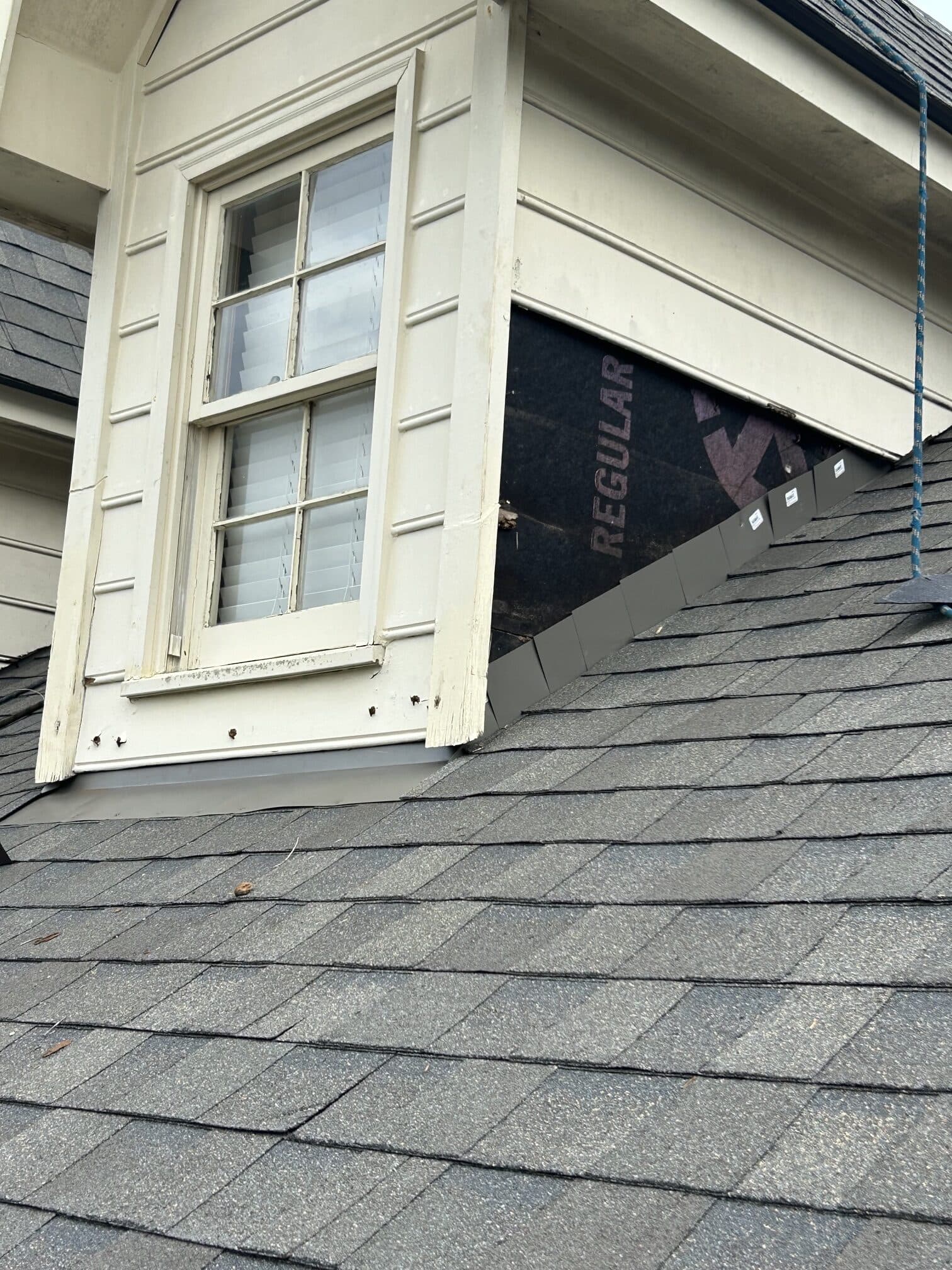 Dark shingle siding detail beside a white framed window