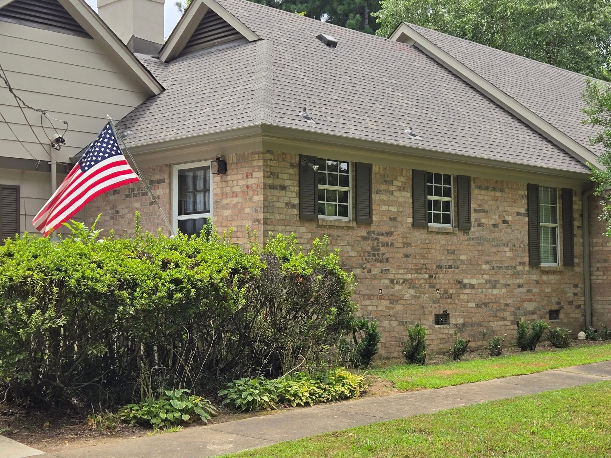 Brick ranch home with an American flag and new shingle roof