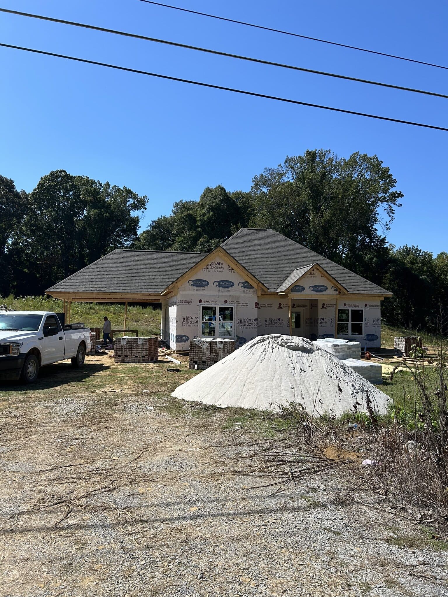 Street view of a ranch home mid-project with covered materials staged in the drive