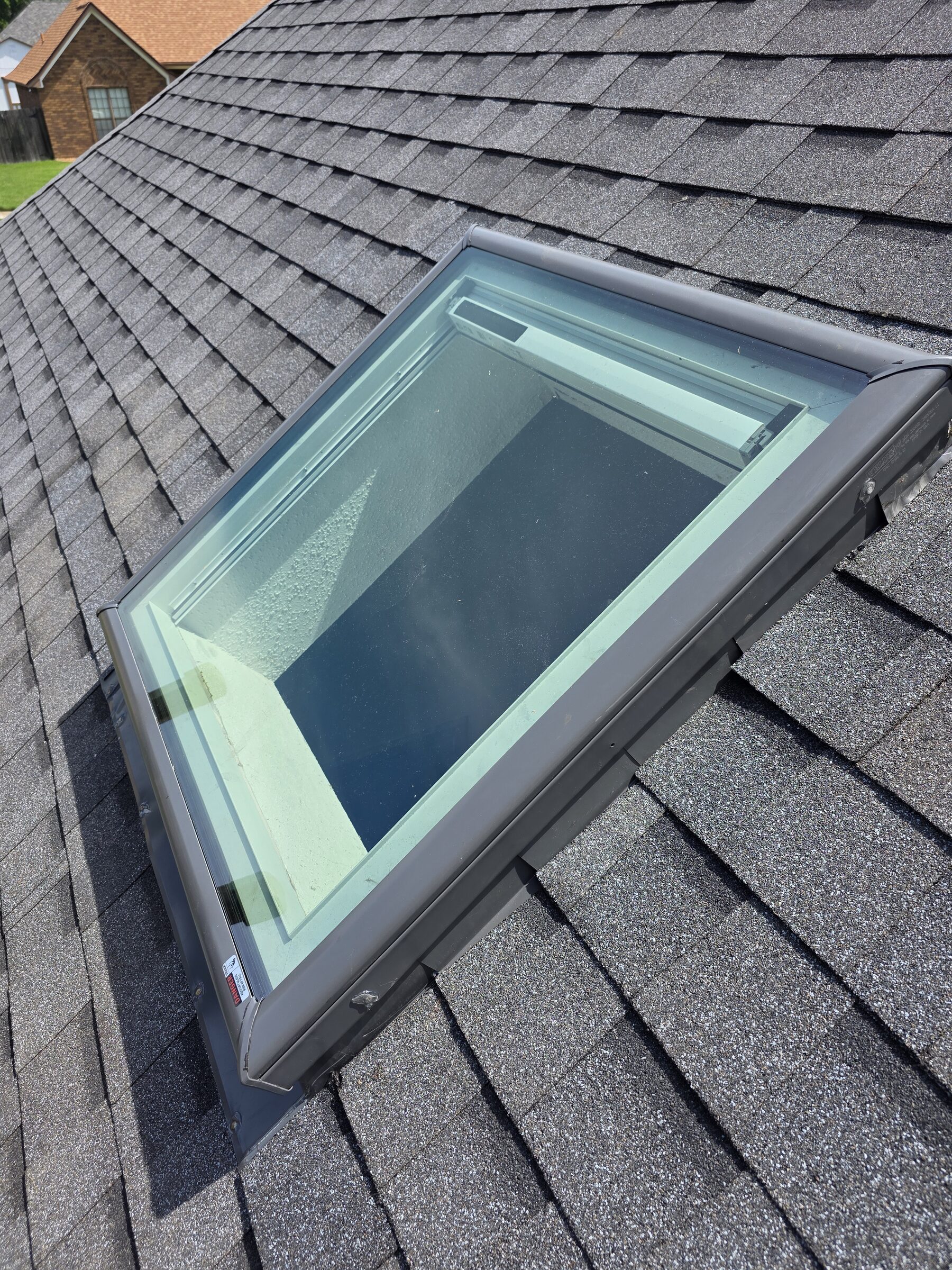 Skylight seen from above on dark architectural shingles