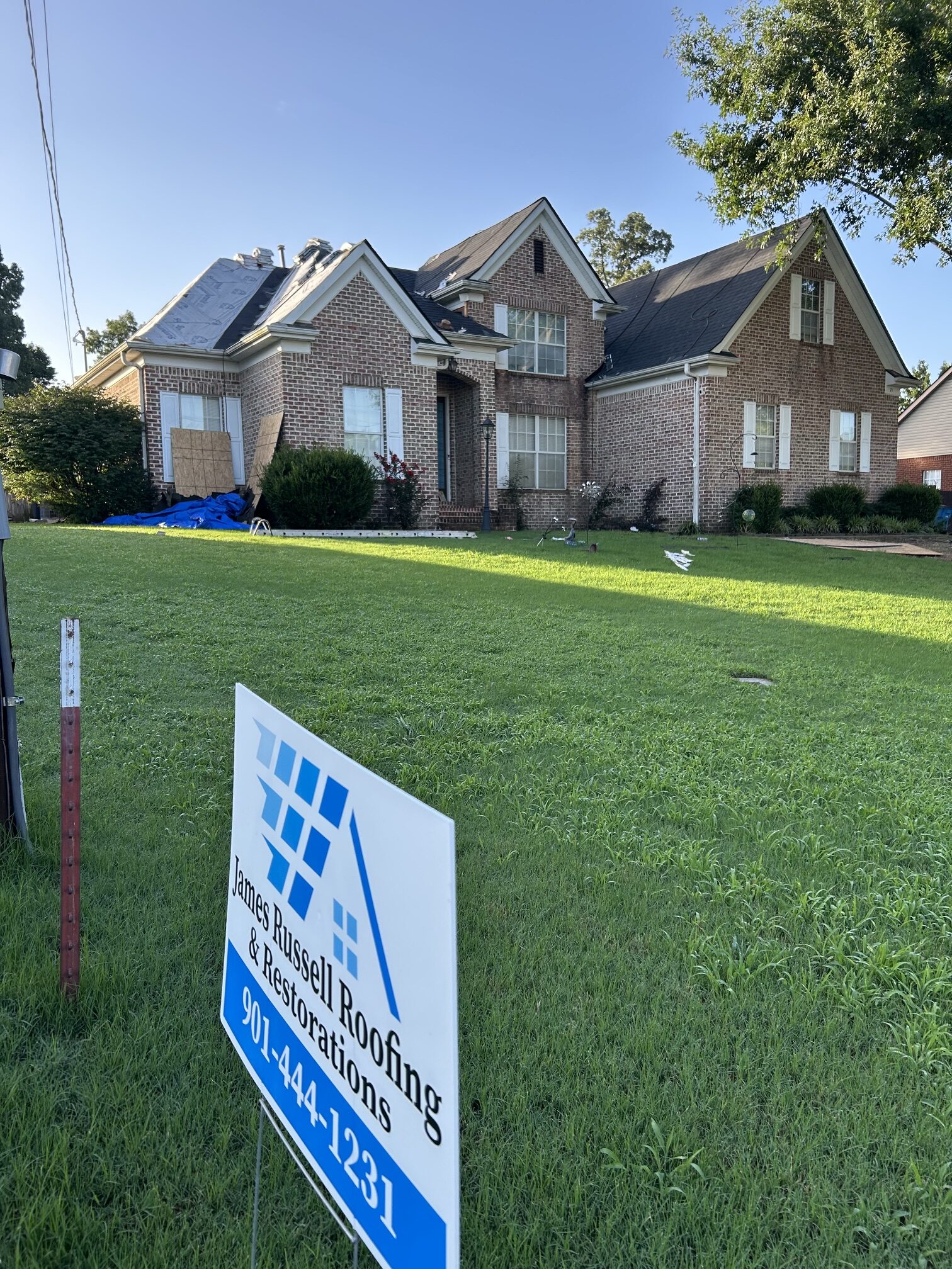 James Russell Roofing yard sign in front of a brick home
