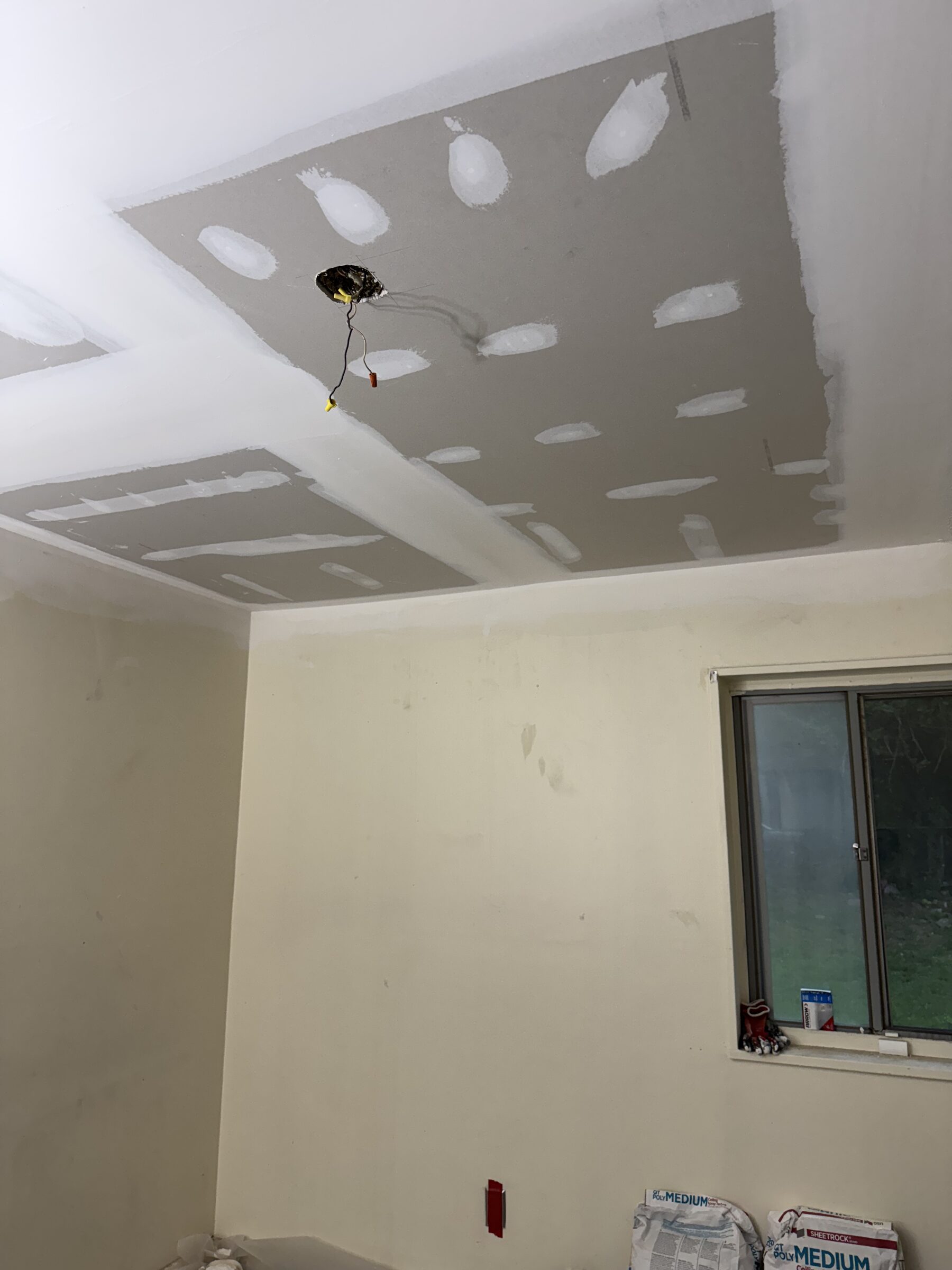 New ceiling drywall with taped and mudded joints around a light fixture opening