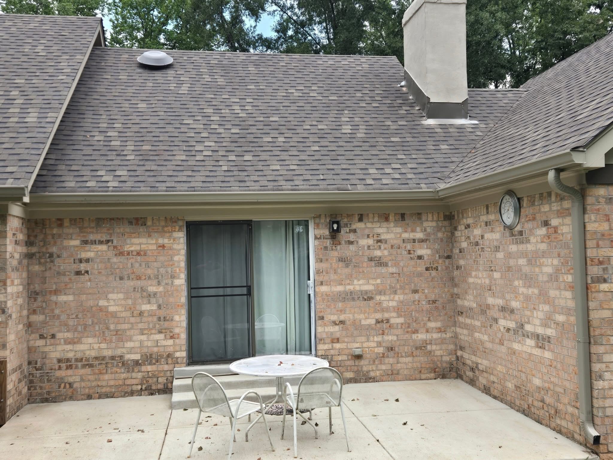 Rear brick patio elevation with a new shingle roof overhead